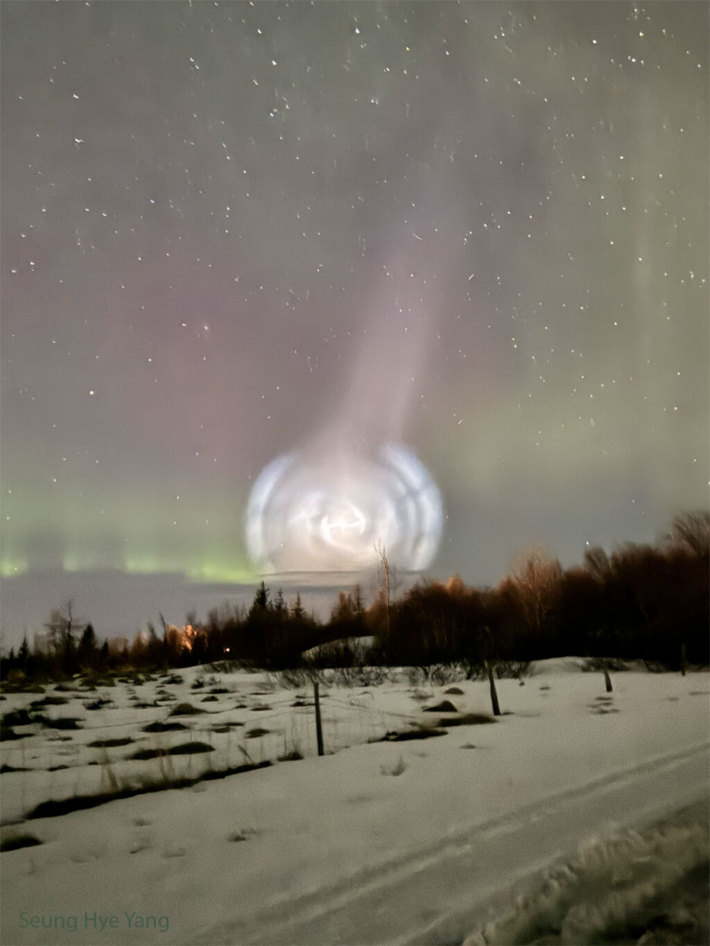Bright white swirled light at the foreground of an active aurora