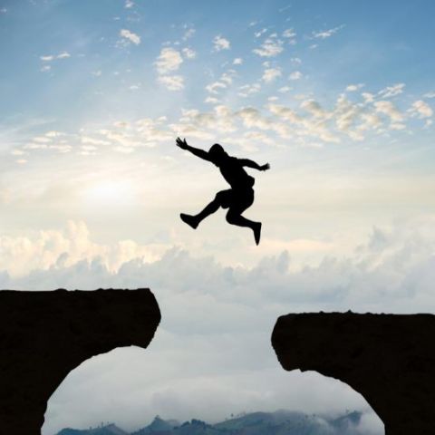 image of a man jumping from one cliff to another