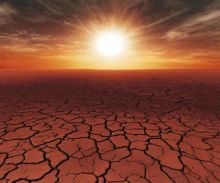 Image of a dry desert with cracked mud and sunshine peeking in the distant horizon