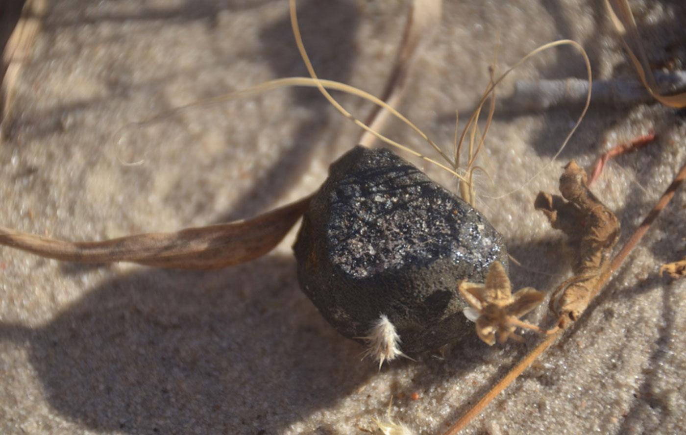 Image of small meteorite found in Botswana against sandy ground