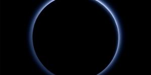 Image of a blue light surrounding a pitch black Pluto